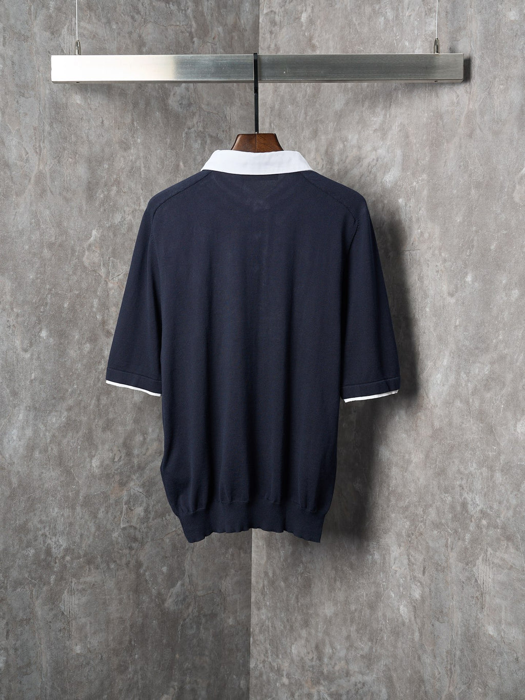 Navy polo shirt back view with white collar trim and three-quarter sleeve cuffs