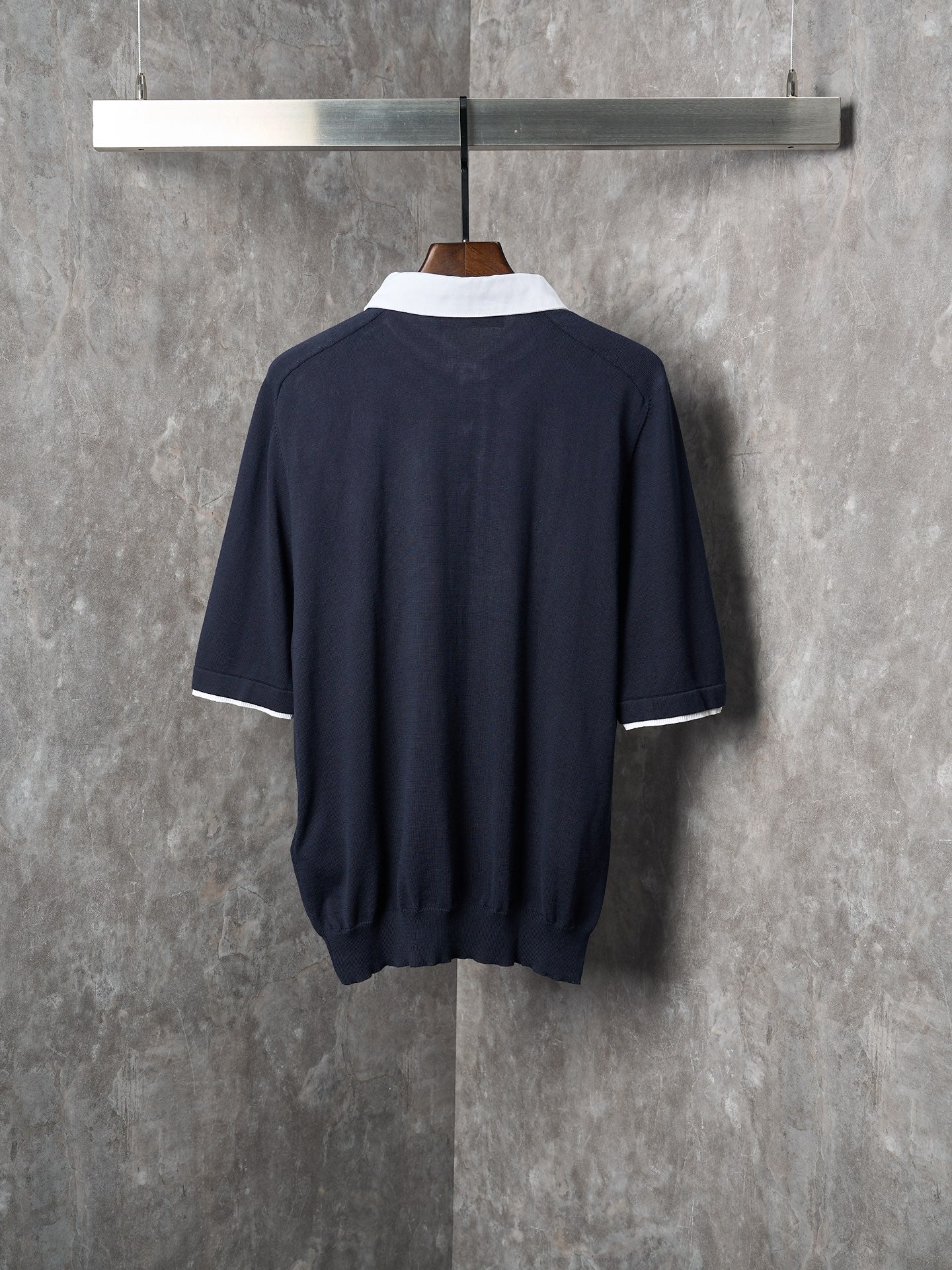 Navy polo shirt back view with white collar trim and three-quarter sleeve cuffs