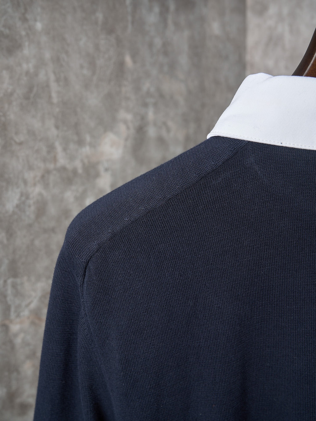 Navy polo shoulder with ribbed knit texture and white inner collar edge.
