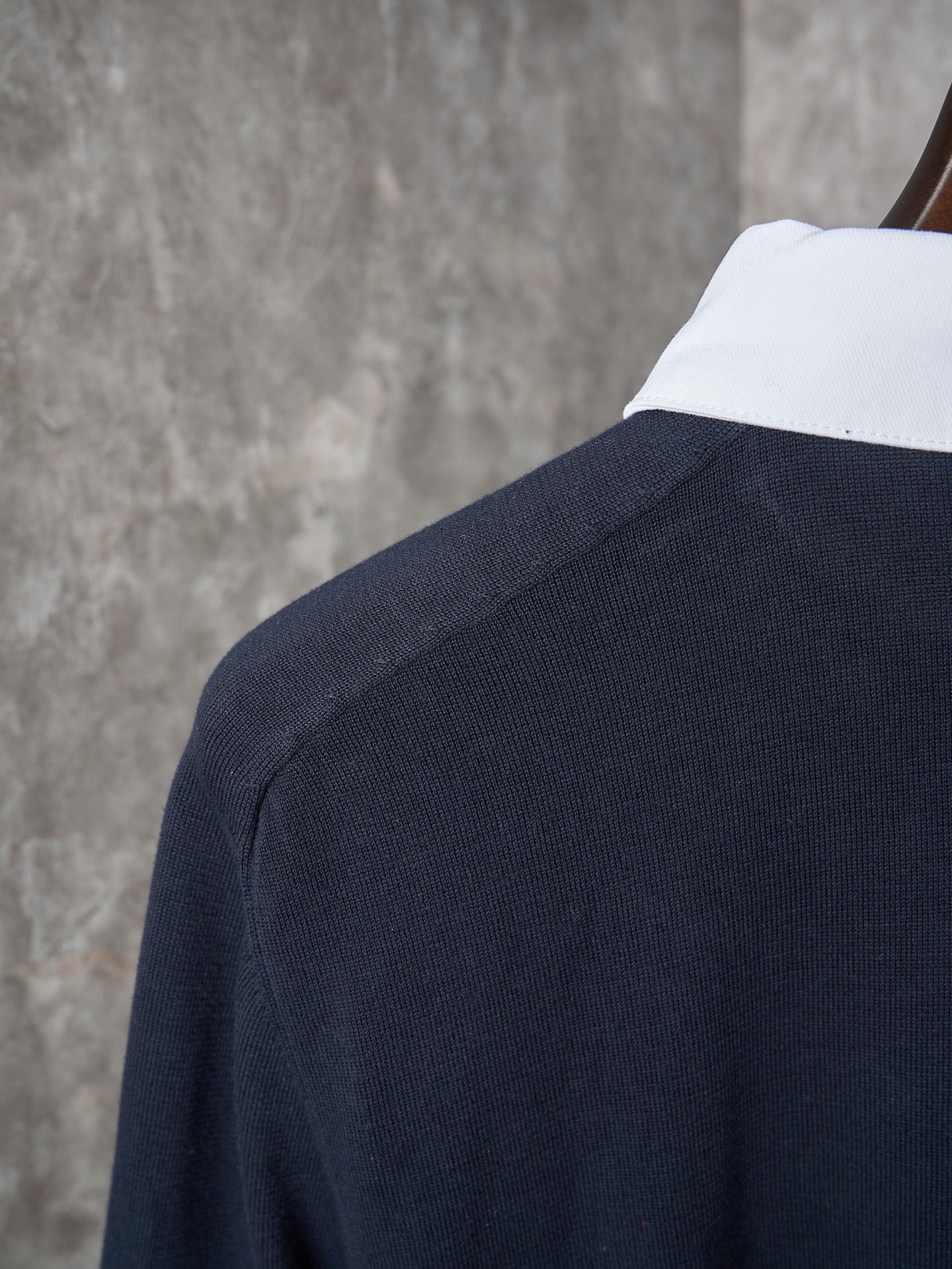 Navy polo shoulder with ribbed knit texture and white inner collar edge.