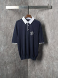 Navy polo shirt with white collar, three-button placket, and embroidered logo on chest