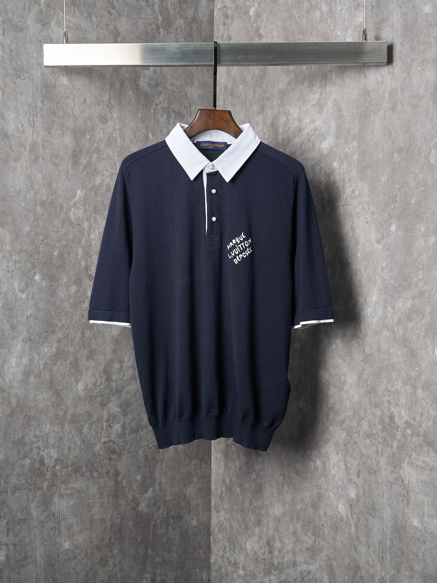 Navy polo shirt with white collar, three-button placket, and embroidered logo on chest