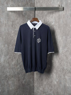 Navy polo shirt with white contrast collar and button placket, short sleeves.