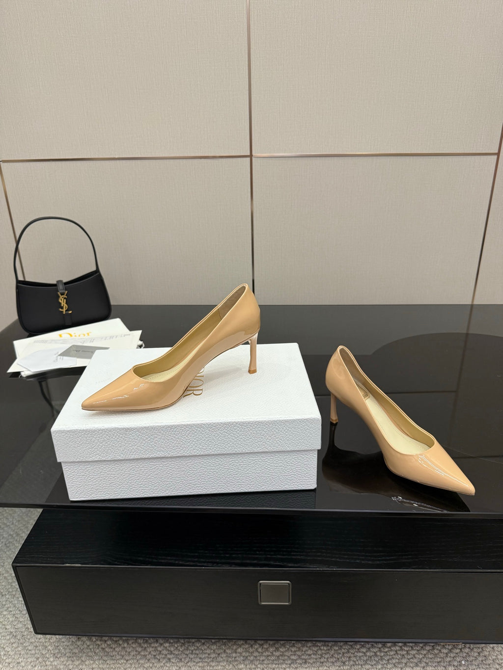 Beige patent pointed-toe pumps with slender stiletto heels, angled view