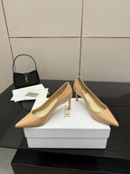 Beige patent pointed-toe pumps with stiletto heels, front angled view