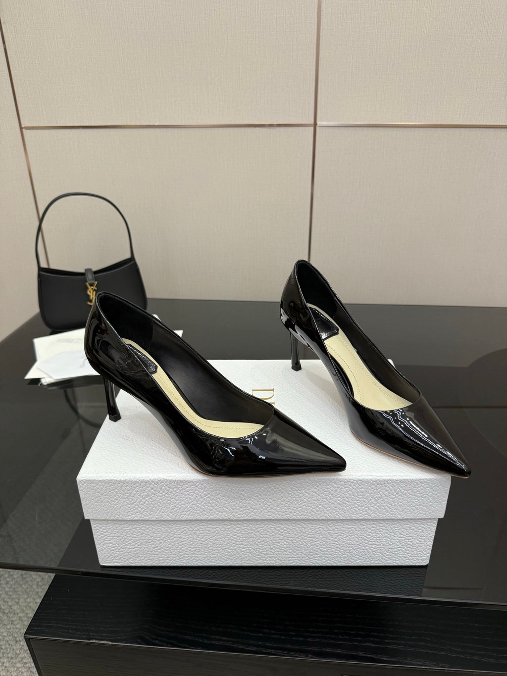 Black patent pointed-toe pump heels with slender stiletto heels, side view on white box