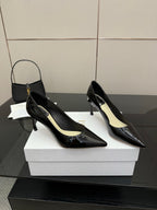 Black patent pointed-toe pump heels with slender stiletto heels, side view on white box