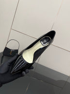 Black patent pointed-toe pump showing light insole, held in hand with glove