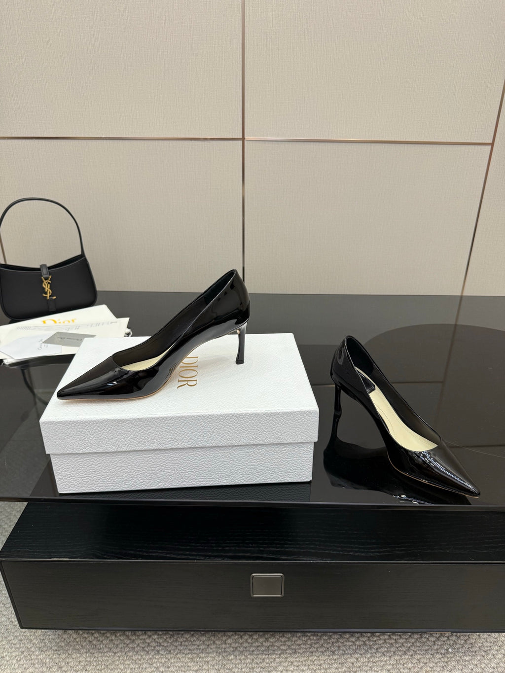 Black patent pointed-toe stiletto pumps, angled view on white box