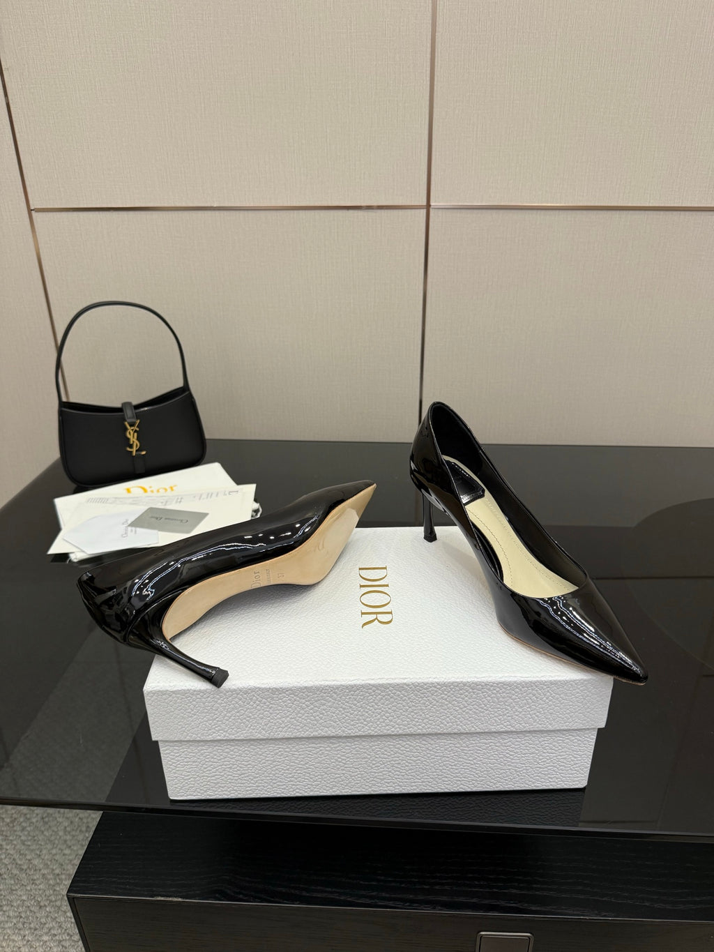 Black patent pointed-toe pumps; one shown with beige insole on white box