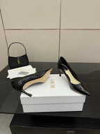 Black patent pointed-toe pumps; one shown with beige insole on white box