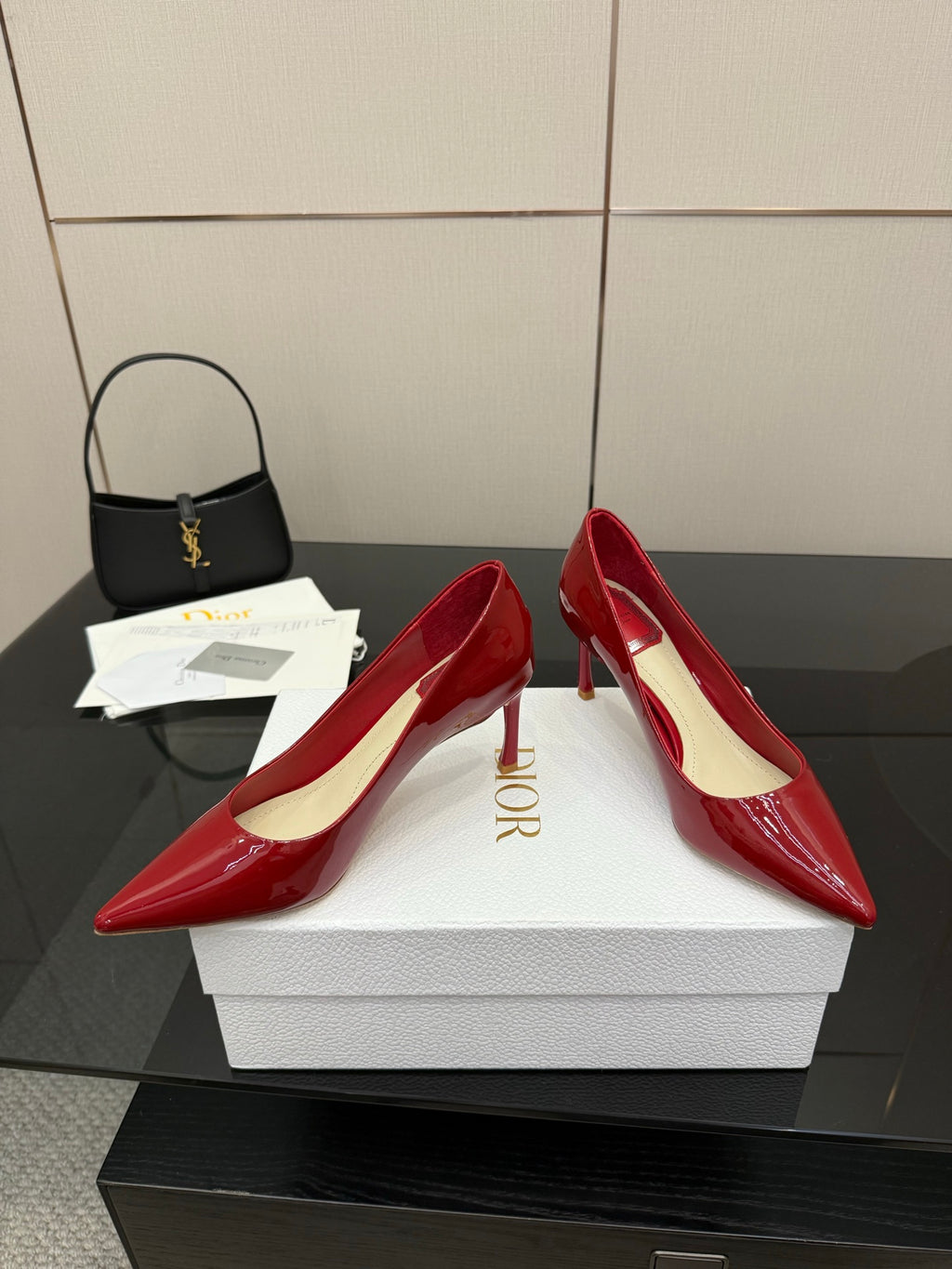 Red patent pointed-toe pumps with stiletto heels, one shoe turned on boxes