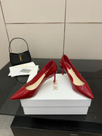 Red patent pointed-toe pumps with stiletto heels, one shoe turned on boxes