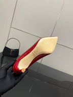 Red and cream pointed-toe pump with stiletto heel, held in a dark glove