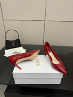Red patent pointed-toe pumps with stiletto heels, heel and toe view on box