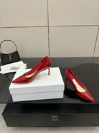 Red patent pointed-toe pumps with stiletto heels, pair on white box