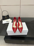 Red patent pointed-toe pumps with stiletto heels, on white shoe boxes
