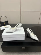 White slingback heels with pointed toe, ankle strap buckle, and slender stiletto heel