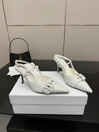 Pair of white slingback heels with buckled strap, pointed toe, and slender stiletto heel