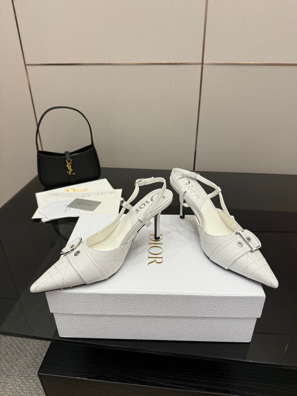 White pointed-toe slingback heels featuring an ankle buckle strap and slim stiletto heel