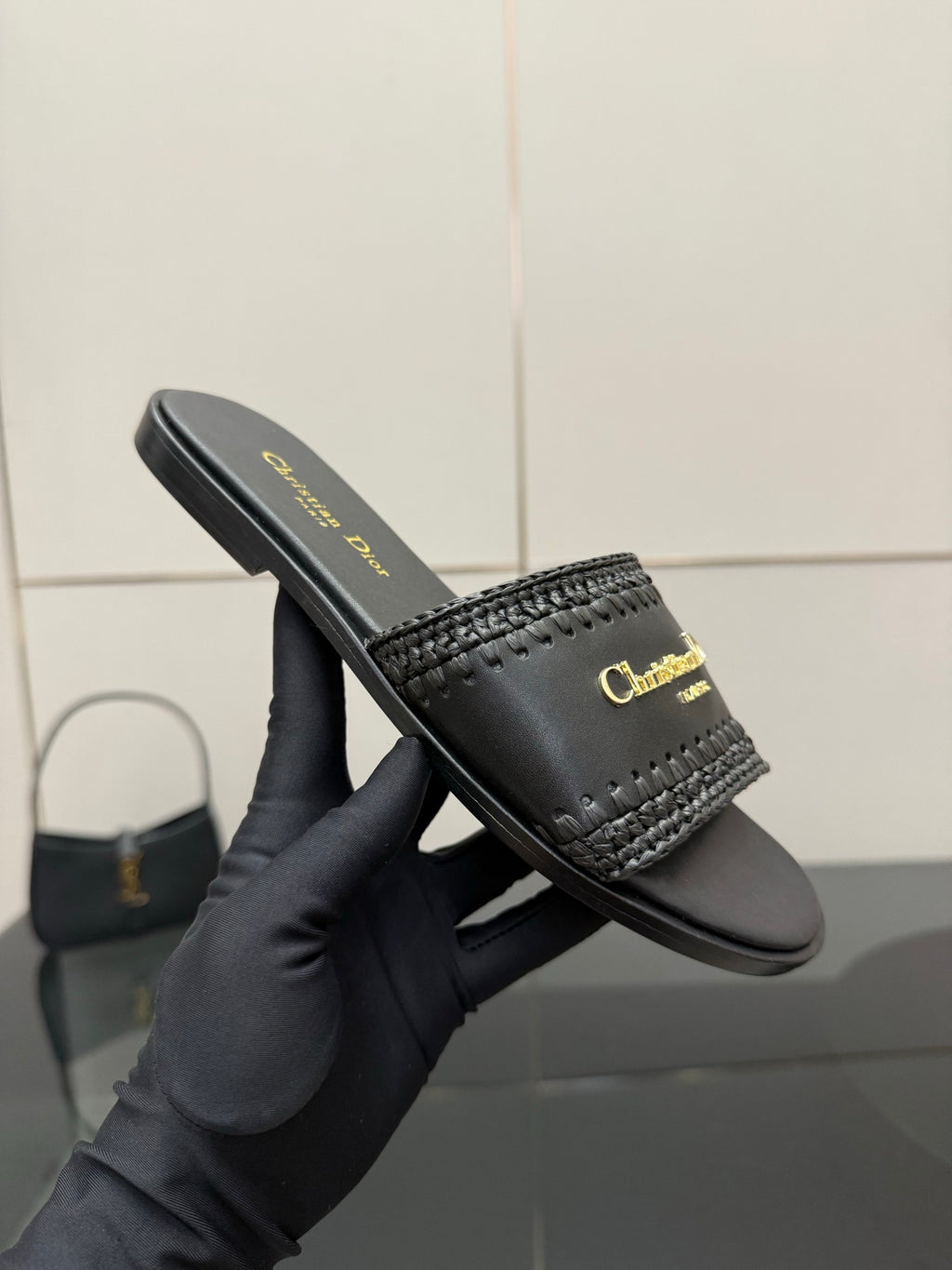Close-up of black leather slide sandal with textured strap and gold Dior lettering
