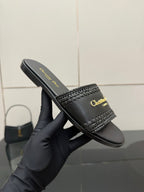 Close-up of black leather slide sandal with textured strap and gold Dior lettering