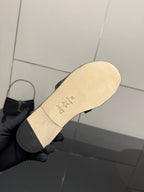 Light tan outsole of a black slide sandal with star-shaped logo and text