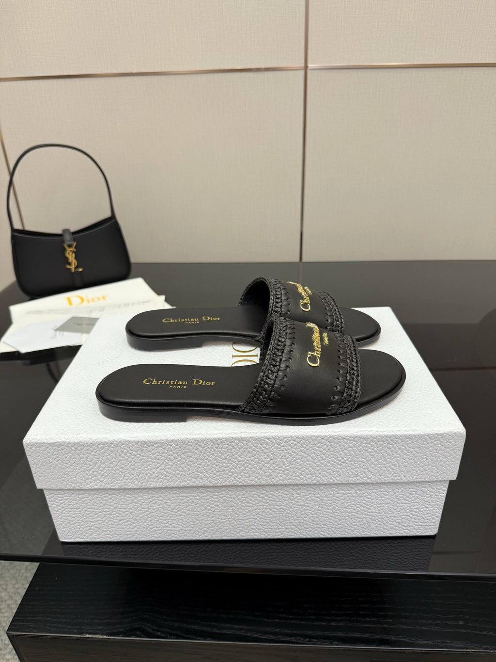 Black slip-on slide sandals with textured band strap and gold Dior logo on footbed