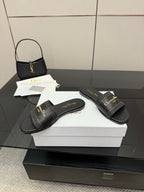 Black leather slide sandals with textured strap, gold Dior script, and open toe