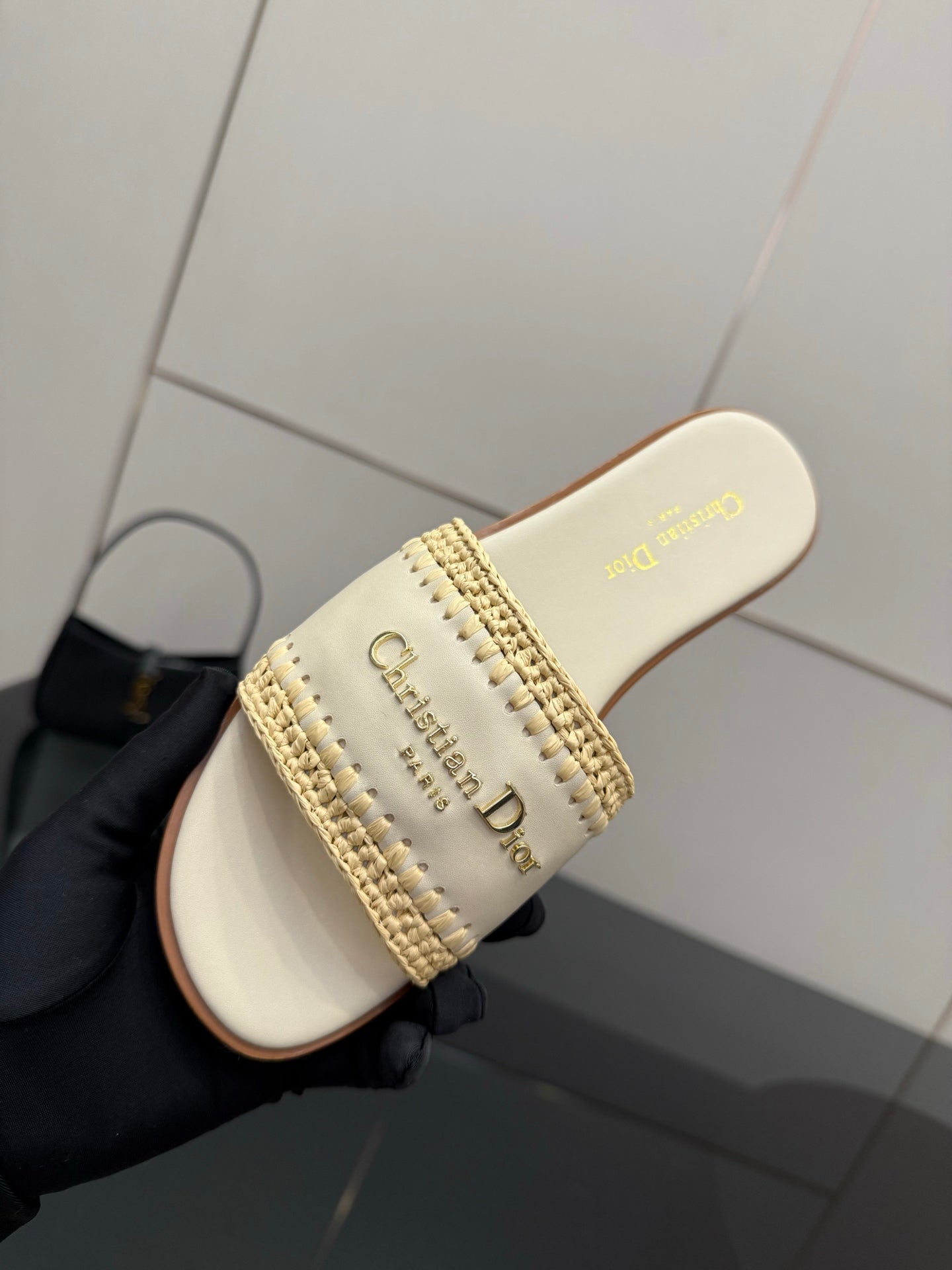 Women's slide sandal close-up, cream footbed with gold logo text and stitched strap
