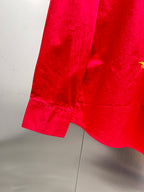 Red long-sleeve shirt hem with side seam and yellow emblem detail