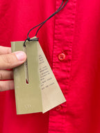 Red long-sleeve shirt with hanging beige product tags on black string