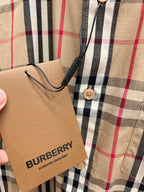 Burberry plaid shirt detail with price tag and buttoned pocket area on beige