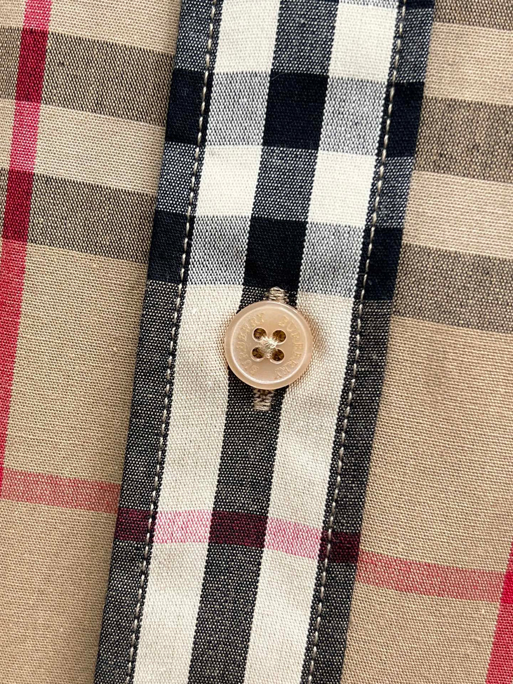 Burberry plaid shirt button close-up on beige fabric with navy and red lines