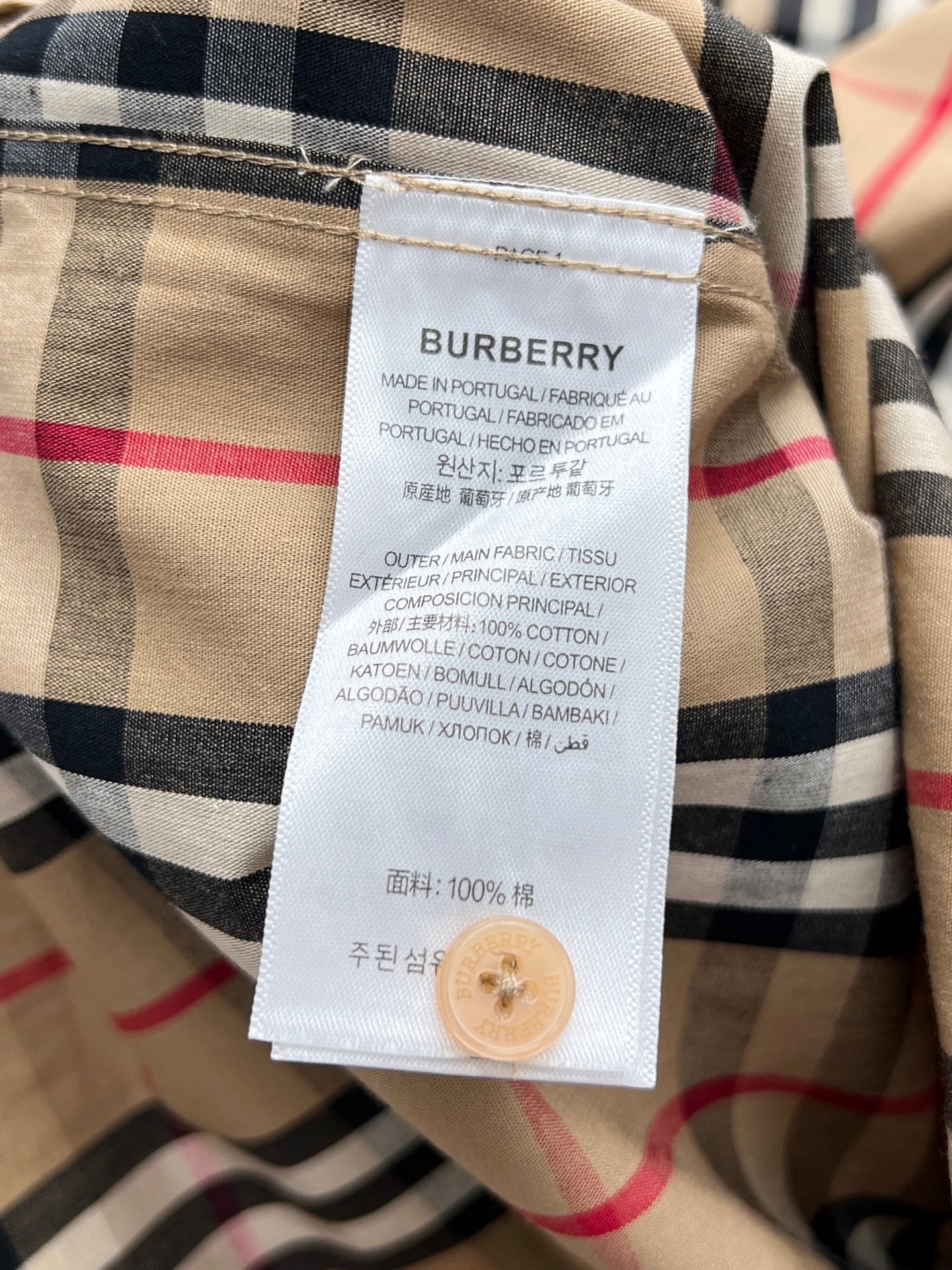 Burberry plaid shirt care label tag on beige, red, and navy check fabric