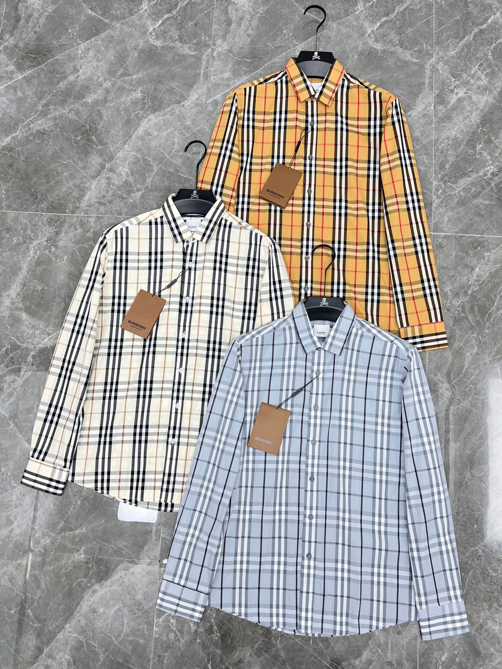 Set of Burberry plaid shirts on hangers: white, orange, and light blue button-ups
