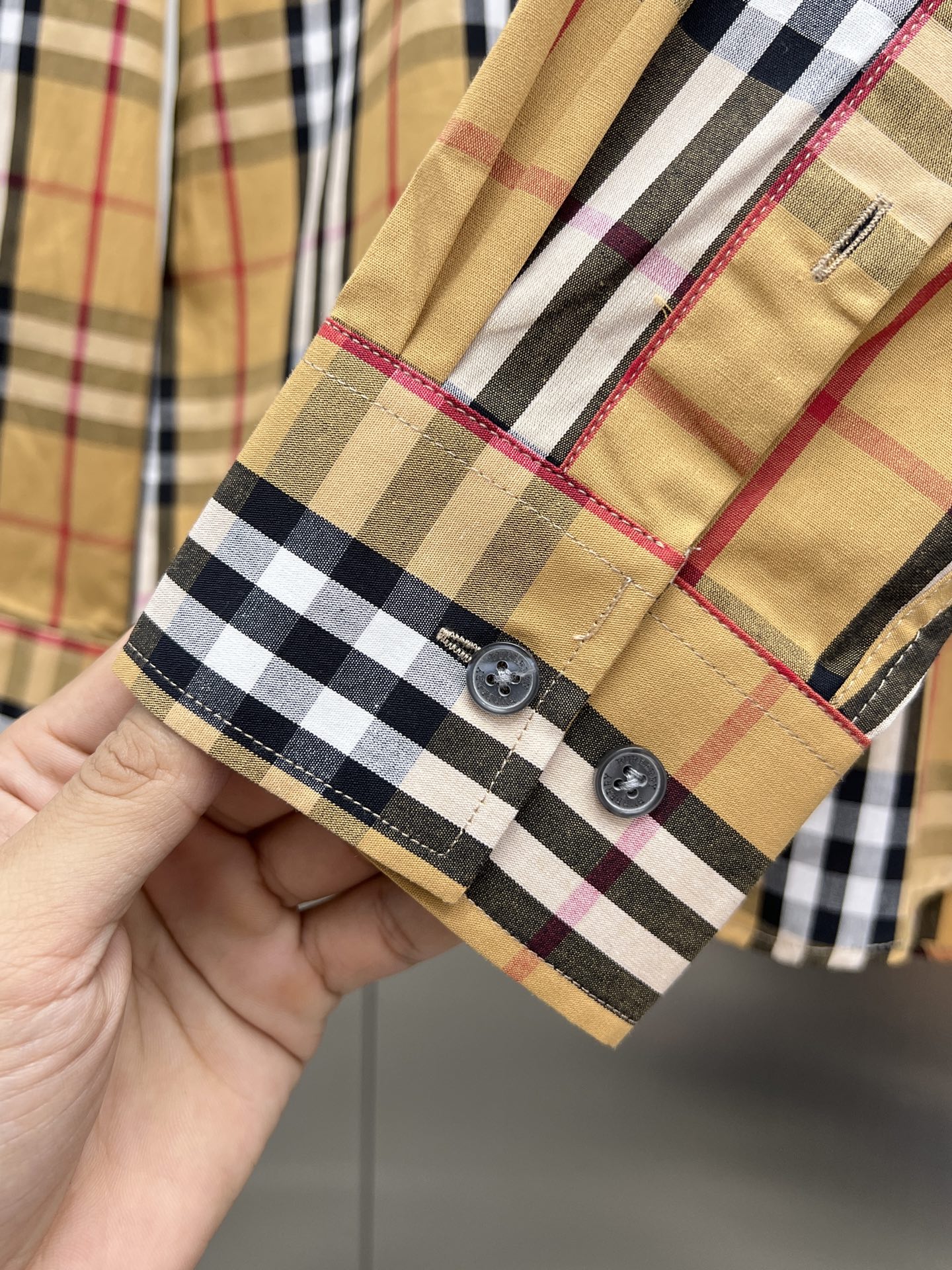 Long-sleeve plaid shirt cuff with two buttons and contrast trim, tan and dark checks