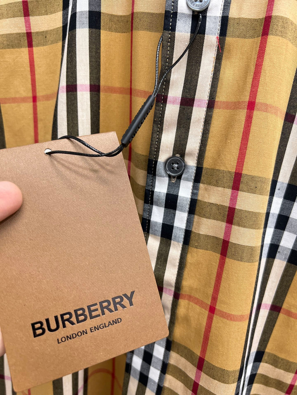 Burberry plaid shirt with attached brown hang tag reading BURBERRY LONDON ENGLAND