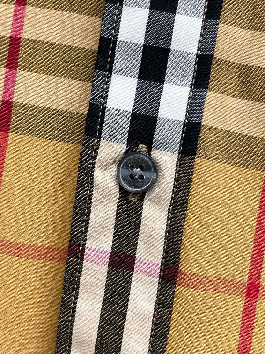 Burberry plaid shirt button close-up with dark stitched placket