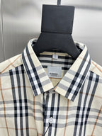 Long-sleeve plaid button-up shirt with button placket, cream with navy and tan checks.