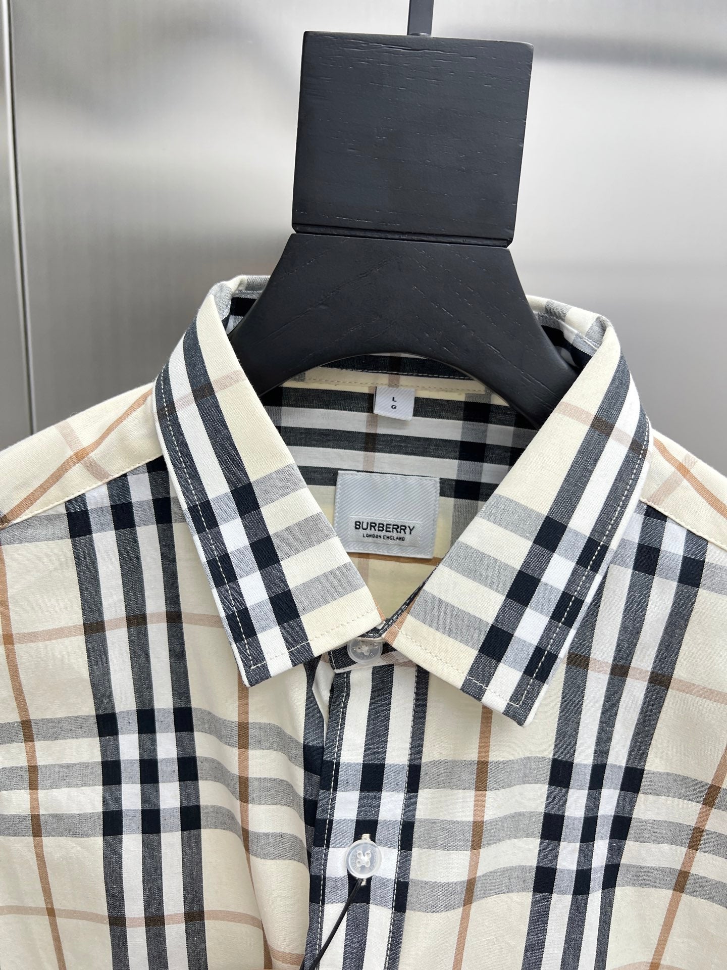 Long-sleeve plaid button-up shirt with button placket, cream with navy and tan checks.