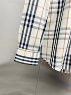 Plaid shirt cuff on long-sleeve button-up, cream with navy and tan checks.