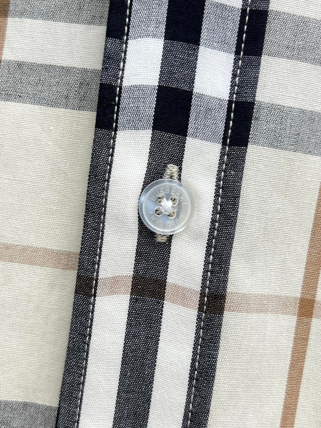 Long-sleeve plaid shirt button detail, cream with navy and tan checks.
