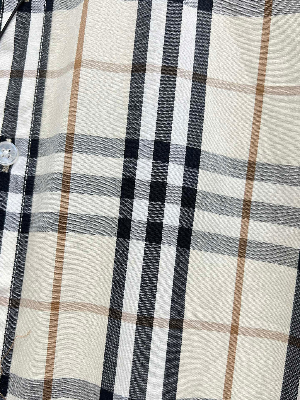 Plaid pattern on long-sleeve shirt, cream ground with navy and tan grid lines.
