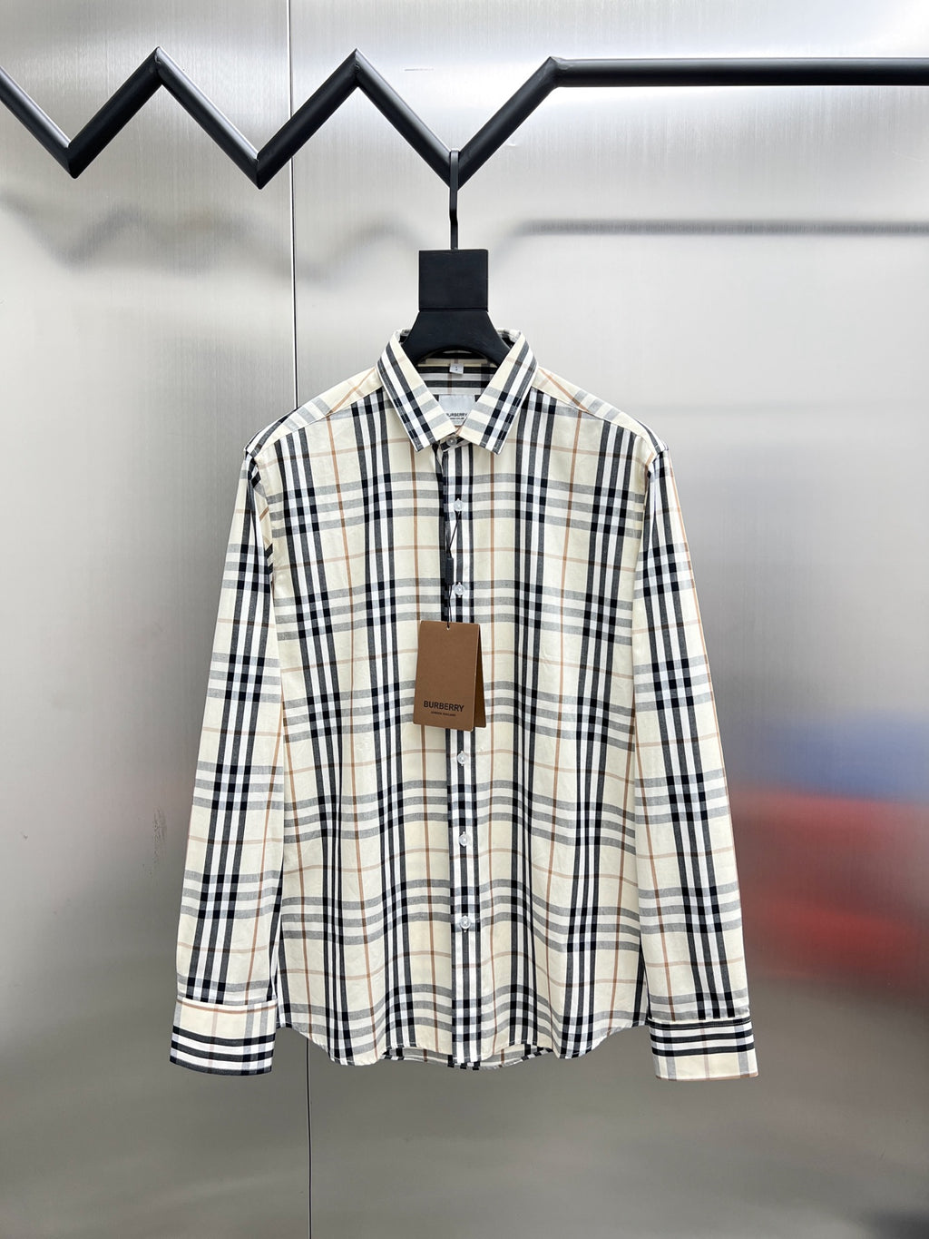 Long-sleeve plaid button-up shirt on hanger, cream with navy and tan checks.