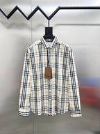 Long-sleeve plaid button-up shirt on hanger, cream with navy and tan checks.