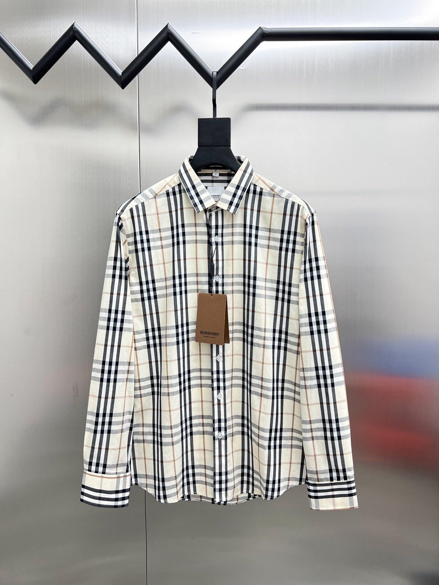 Long-sleeve plaid button-up shirt on hanger, cream with navy and tan checks.