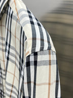 Plaid woven sleeve on long-sleeve shirt, cream with navy and tan lines.