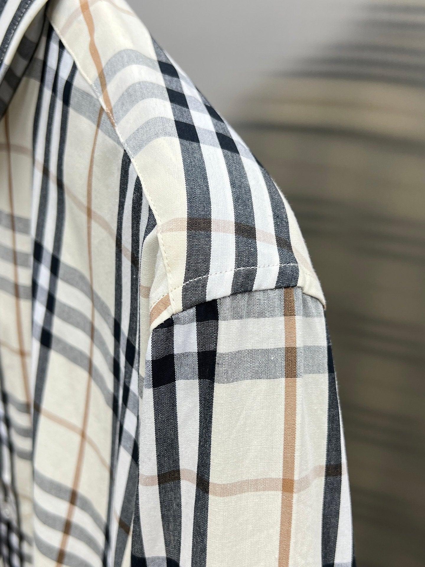 Plaid woven sleeve on long-sleeve shirt, cream with navy and tan lines.