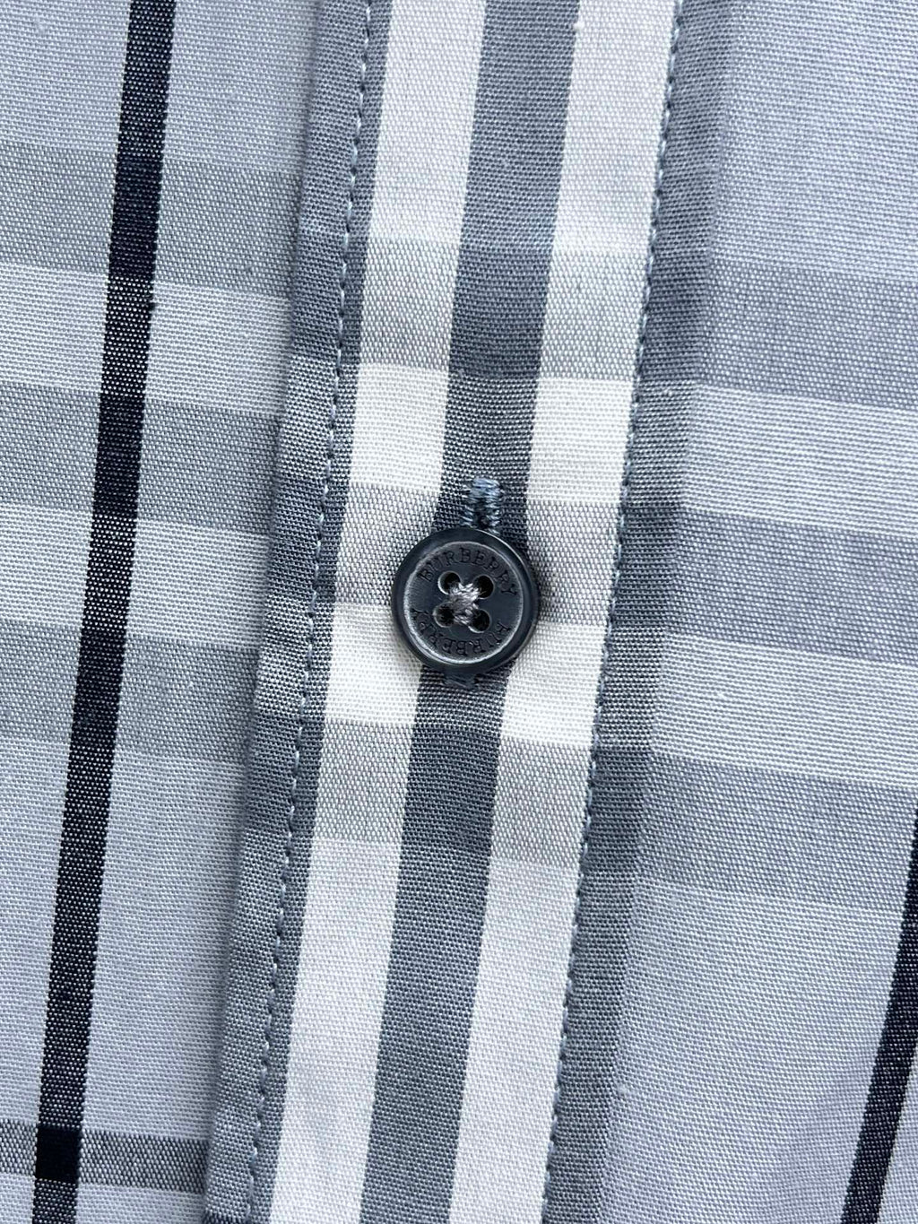 Burberry plaid shirt button close-up on light blue and white check fabric